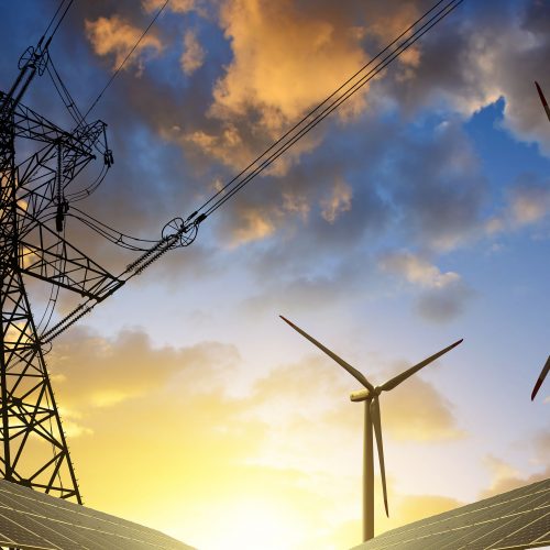 power lines and wind turbines over a solar field at sunset