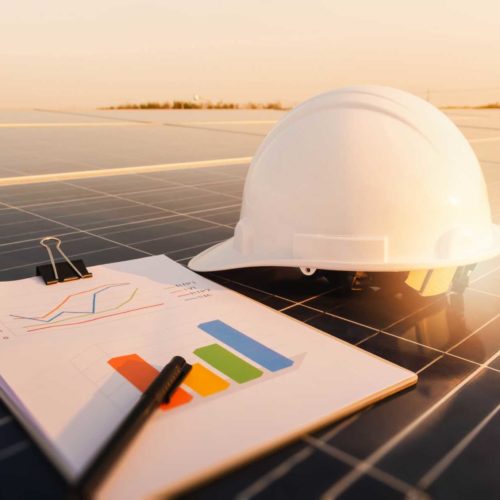 construction helmet and data clipboard on solar panel