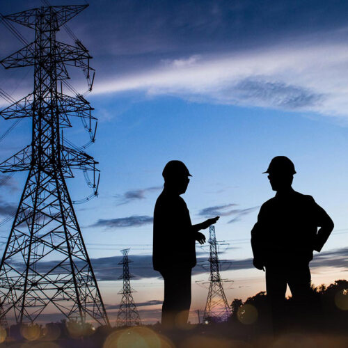 two technicians by a powerline at twilight